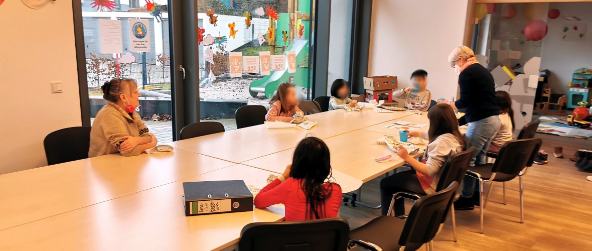 Crêpes essen im Leseclub Kinder und Mitarbeiterinnen des Leseclubs sitzen am Tisch und essen Crêpes