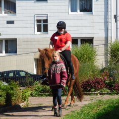 Reiterin auf einem Island-Pferd, das von einem Mädchen geführt wird.