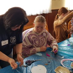 Eine Betreuerin hilft einem Kind beim Kreativtag des TVP