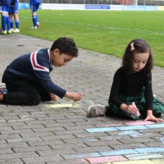 Kinder malen mit Kreide auf das Pflaster im Stadion
