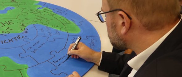 Oberbürgermeister Markus schreibt auf eine Weltkugel Oberbürgermeister Markus schreibt auf eine Weltkugel