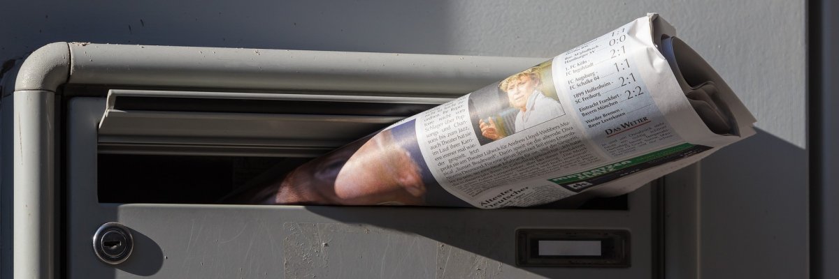 Ein Briefkasten in dem eine Zeitung steckt.