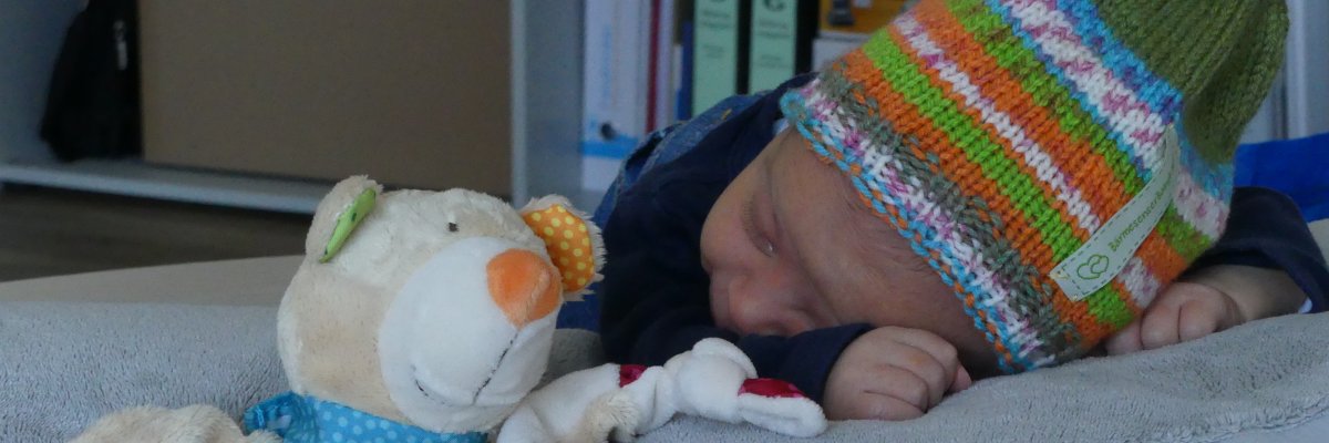 Baby mit Bäby-Kapp aus dem Willkommenspaket Baby mit Bäby-Kapp aus dem Willkommenspaket